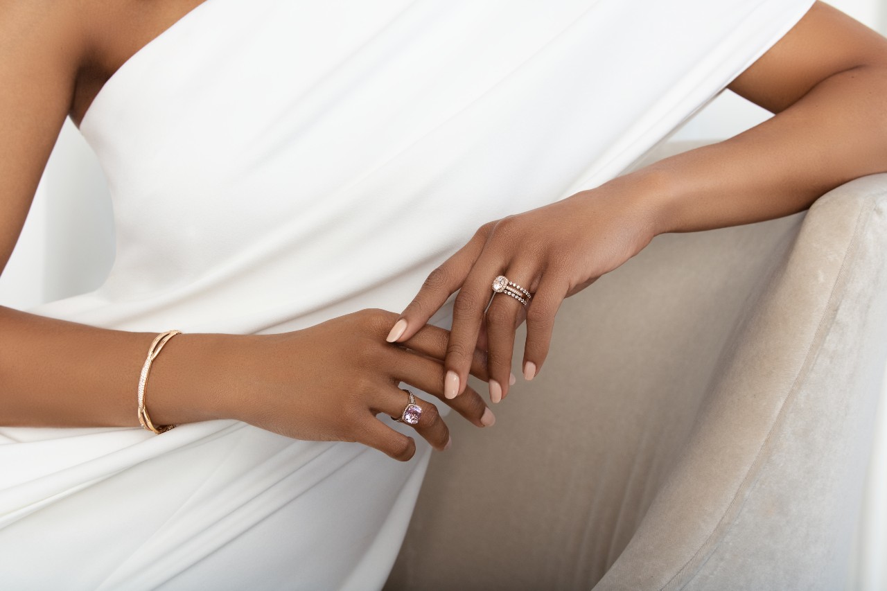 Woman Sitting on A Chair Wearing a TACORI Bracelet, Gemstone Ring, and a Bridal Set of Engagement Ring and Wedding Band