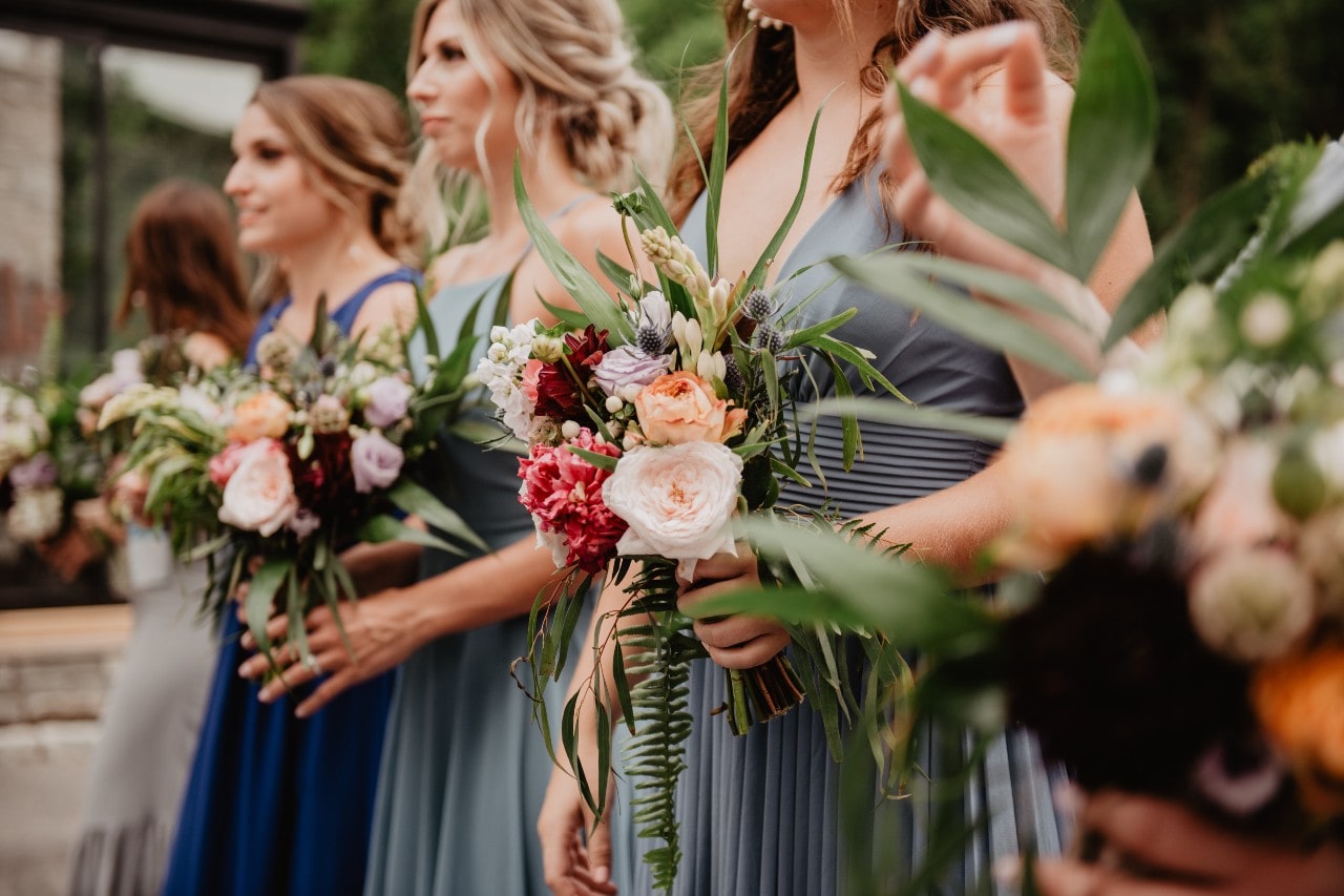 A low shot of five bridesmaids, each holding a stunning bouquet.