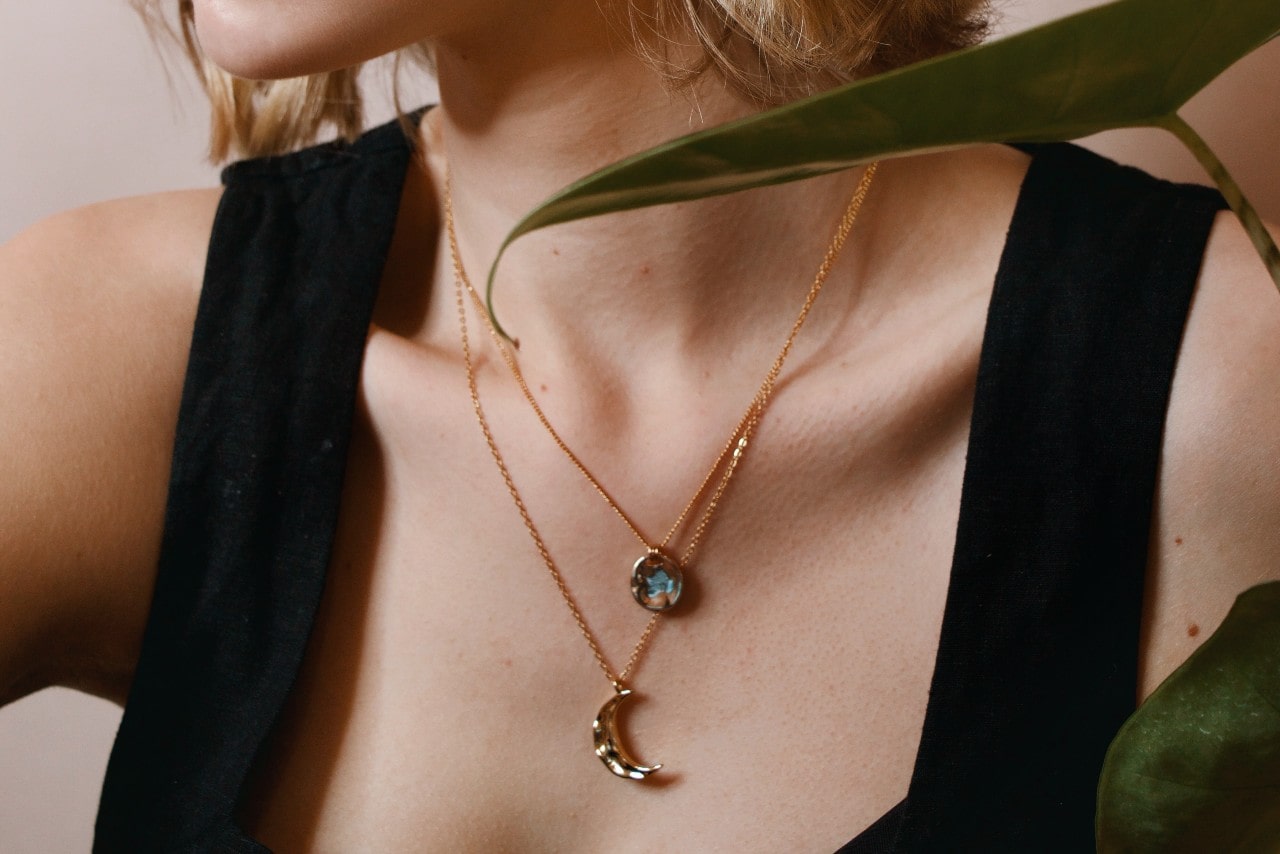 a woman’s neckline adorned with layered pendant necklaces