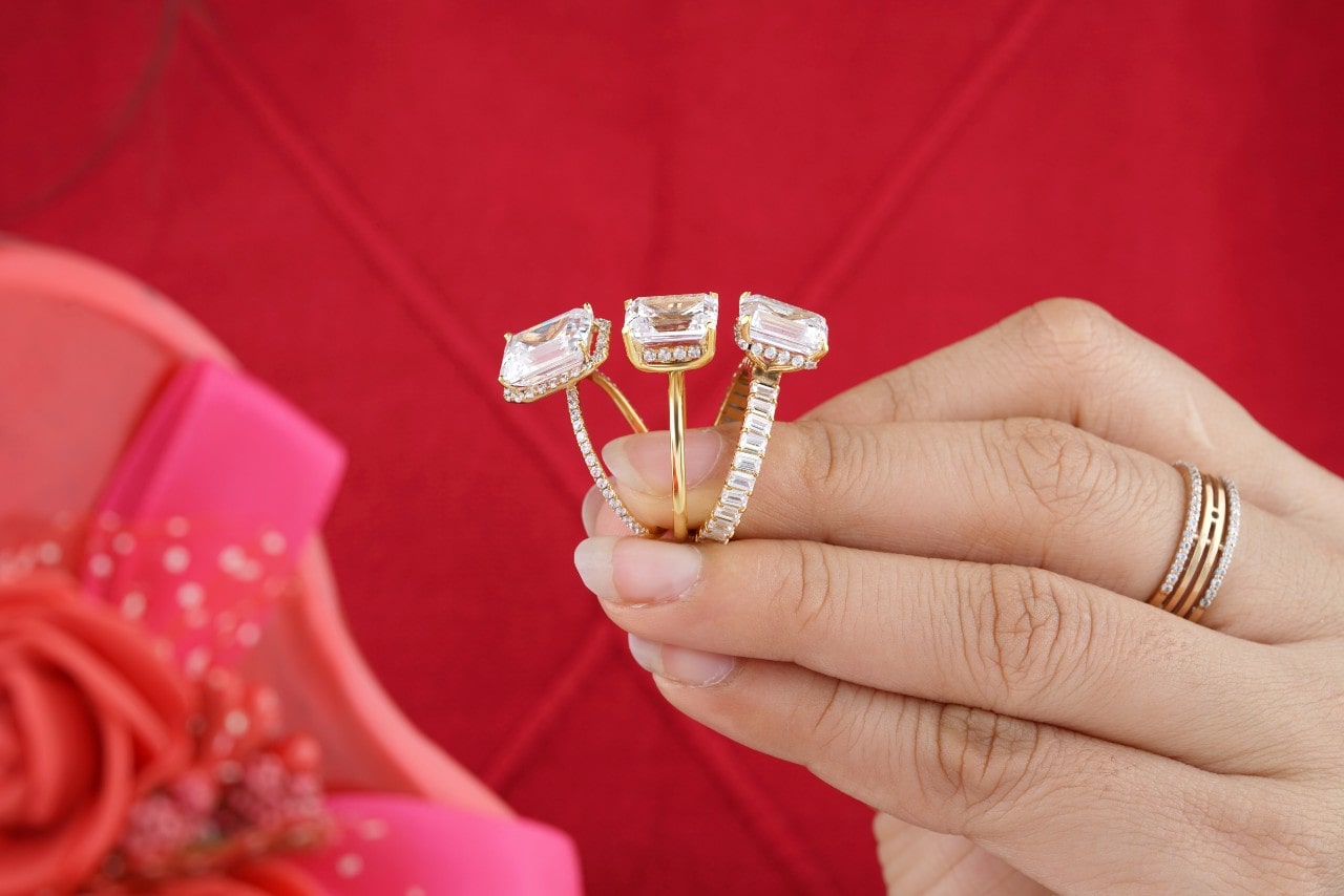 A close-up of a woman’s hand holding three stunning diamond rings.