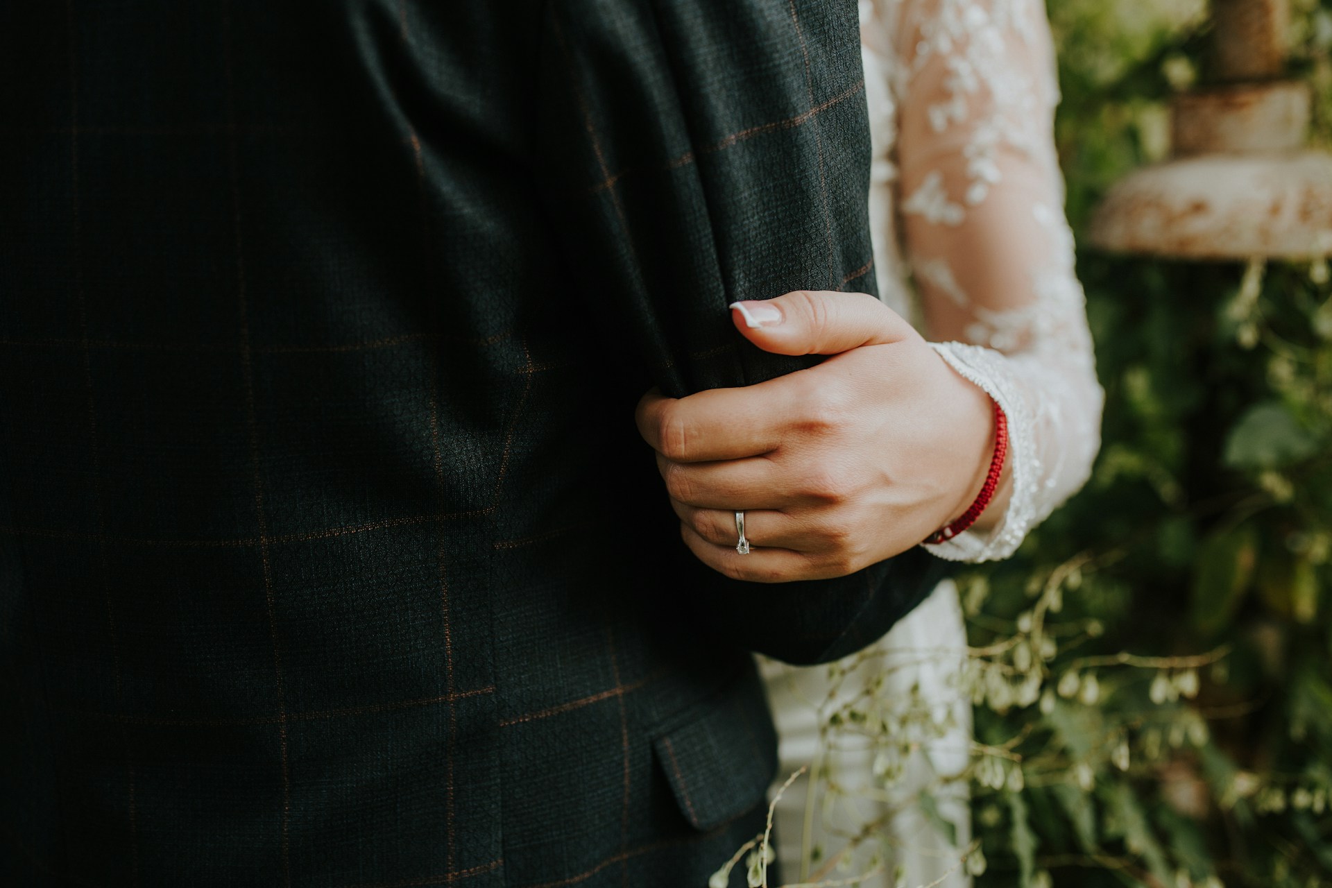 A bride holding on to the arm of her groom with a view of her diamond engagement ring