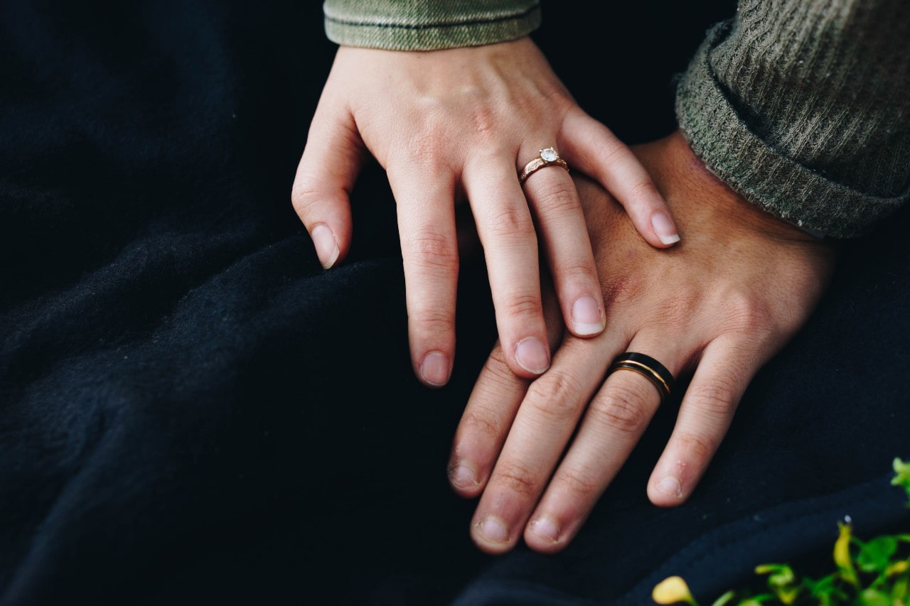 Couple’s hands touching and can see her engagement ring and his wedding band