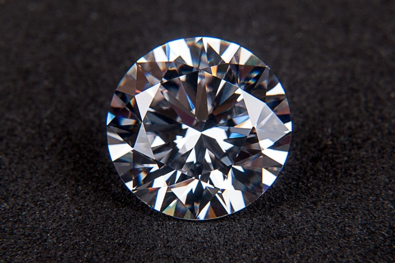 A close-up of a spectacular round-cut diamond on a soft fabric backdrop.