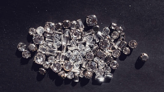 Many small lab grown diamonds of multiple cuts on a dark background.