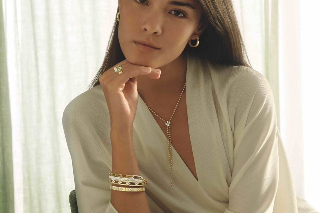 Woman wearing Roberto Coin yellow gold and diamond bangles, chain bracelet, necklace, rings, and earrings Woman wearing Roberto Coin yellow gold and diamond bangles, chain bracelet, necklace, rings, and earrings