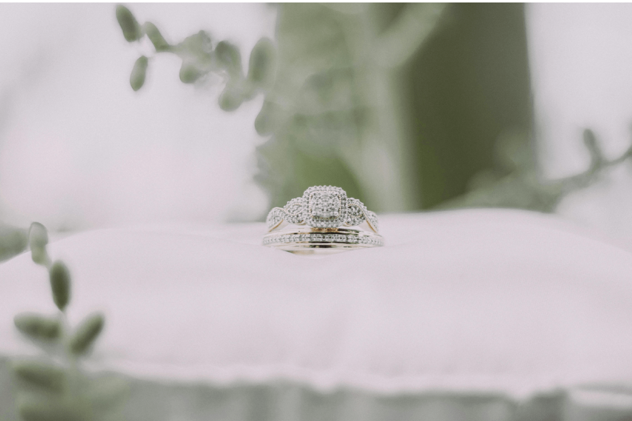 A matching bridal set on a white pillow surrounded by greenery.